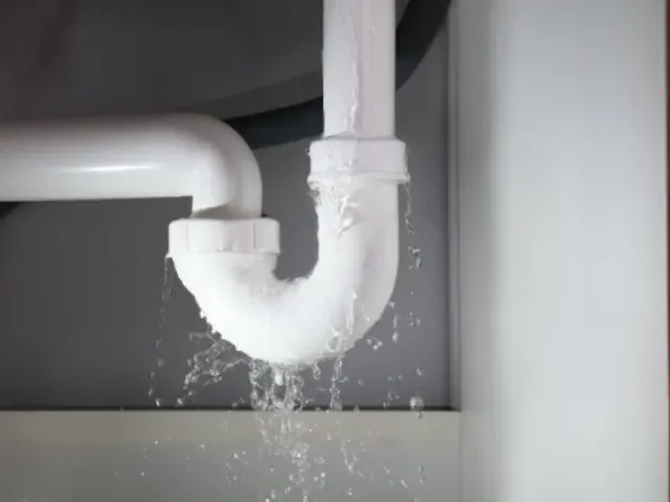 Water spraying from a sink drain trap pipe under a basin